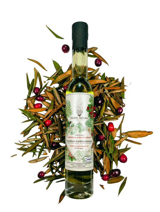 Bouteille de sirop boréal canneberge et thé du Labrador 200 ml par Kabir Kouba Inspiration, décorée de canneberges et de branches de thé du Labrador
